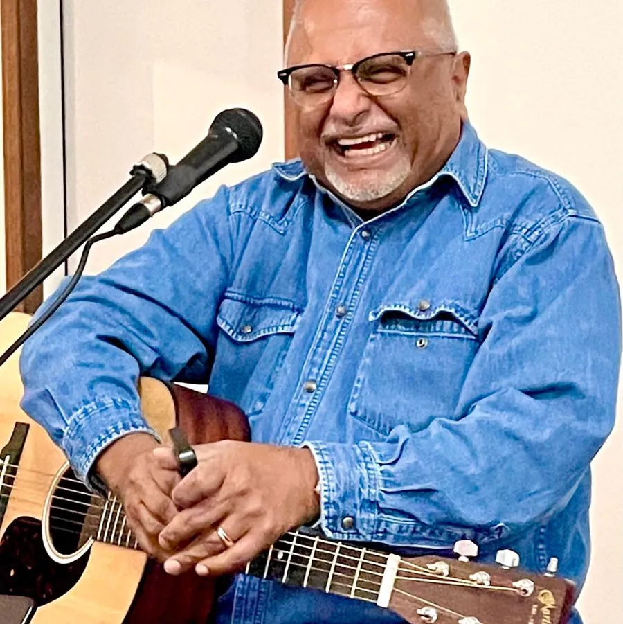 Bernie laughing with his guitar at a microphone