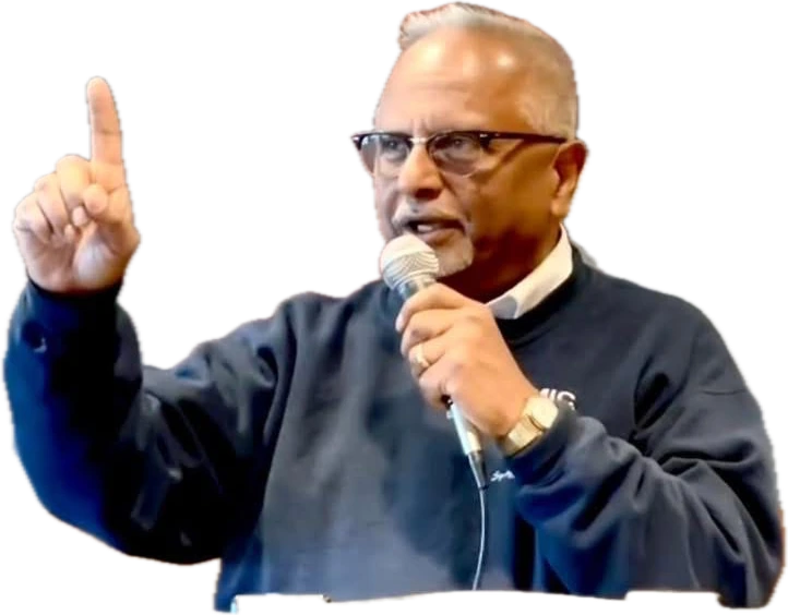 Bernie Lutchman preaching with a microphone, one finger raised